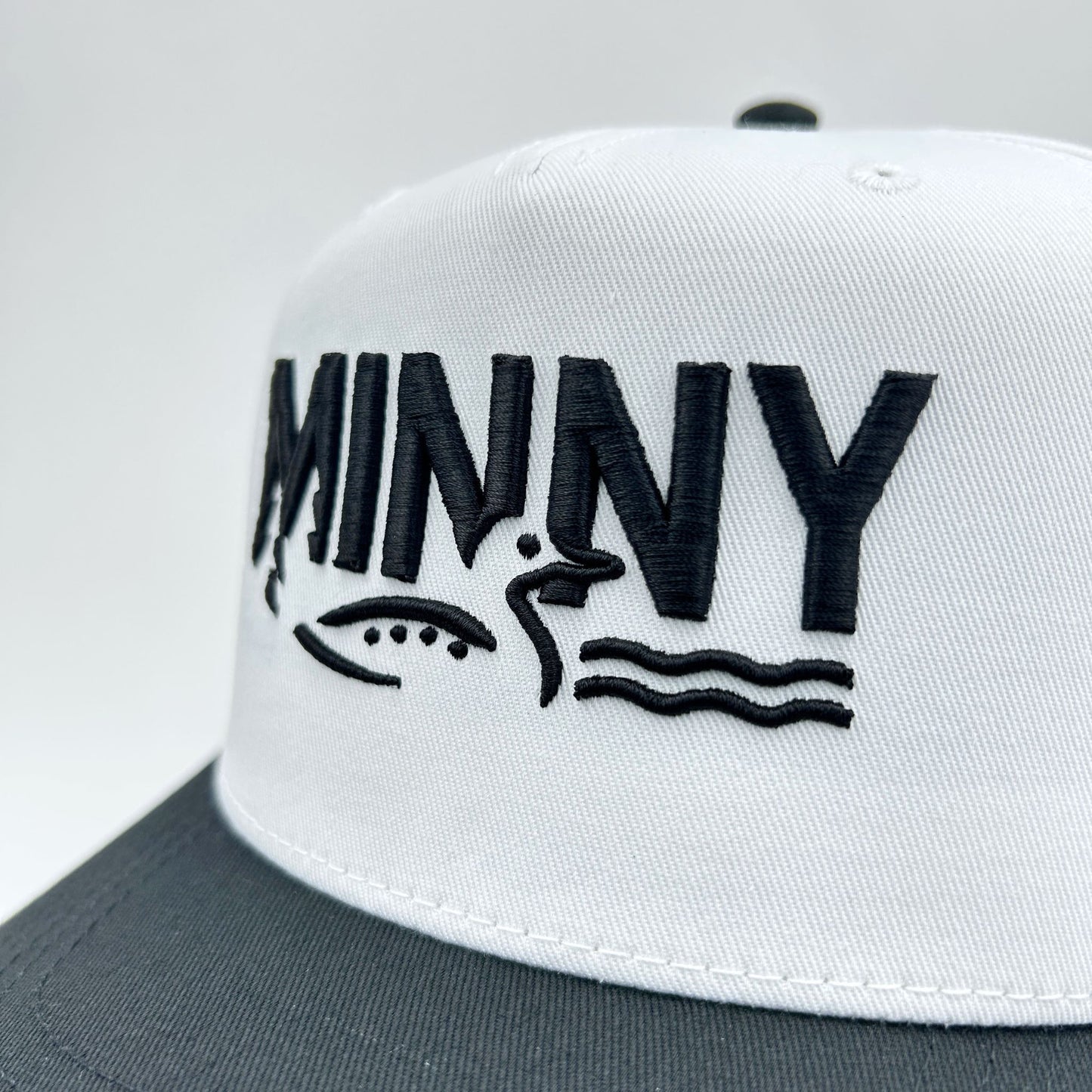 White cap with black text and graphics on a gray background