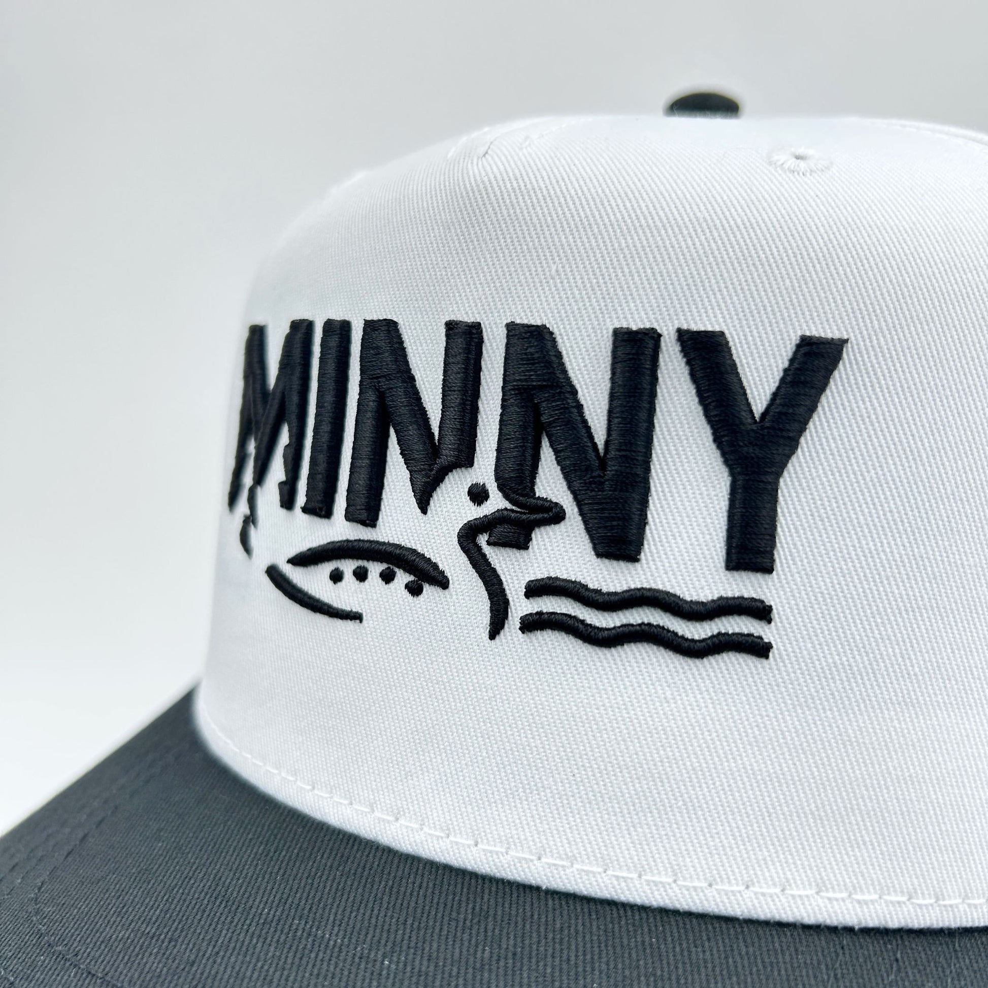 White cap with black text and graphics on a gray background