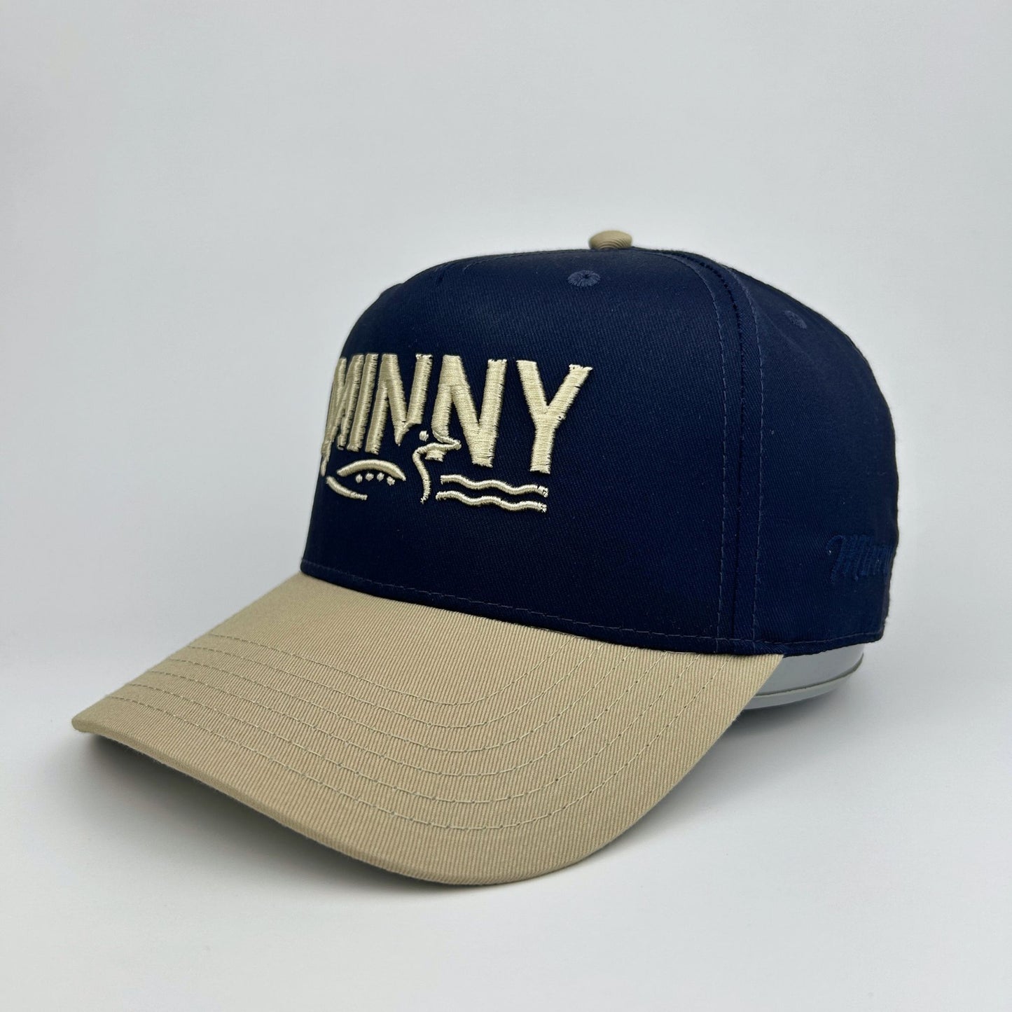 Navy and beige cap with 'MINNY' branding on a light gray background