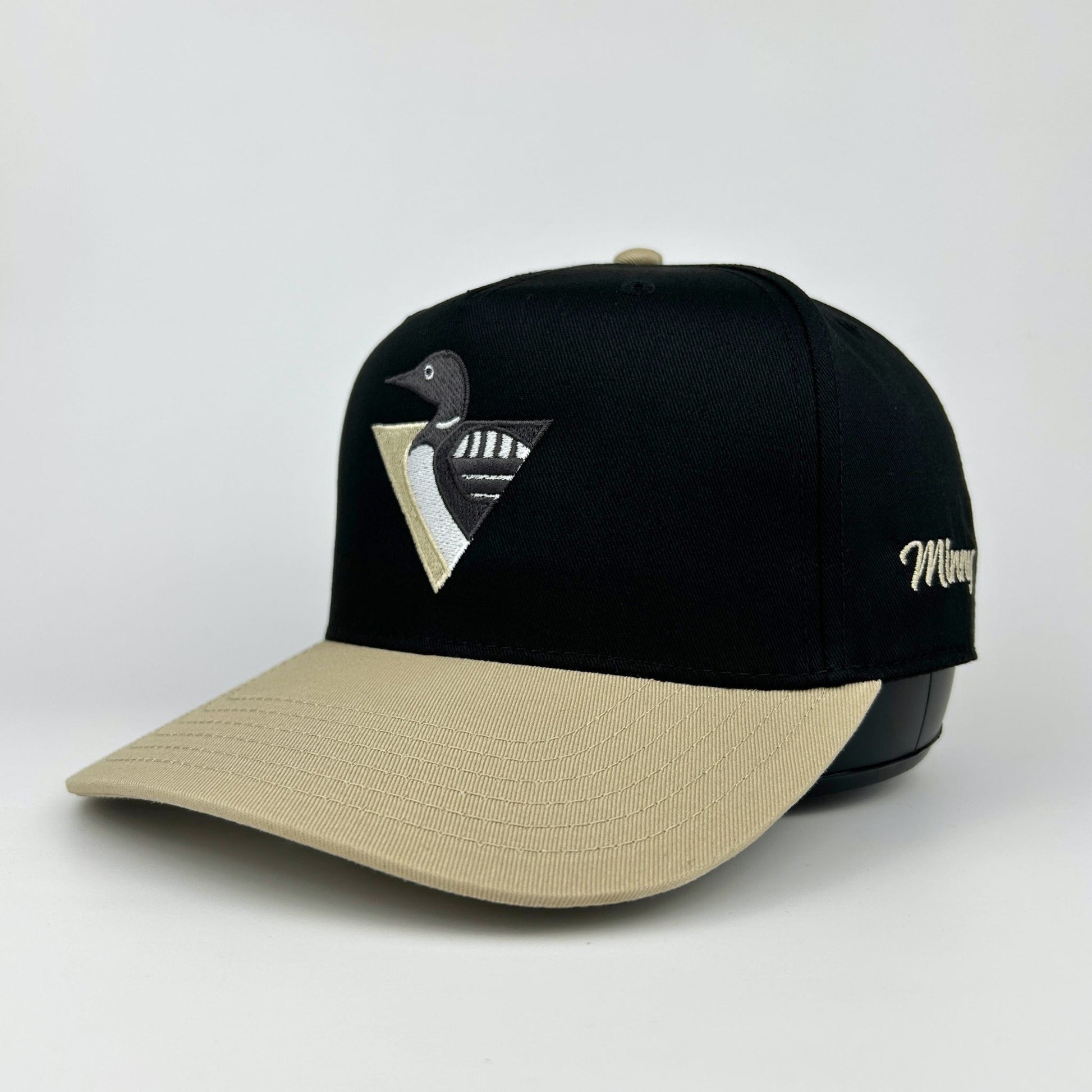Black and beige cap with a logo on a light gray background