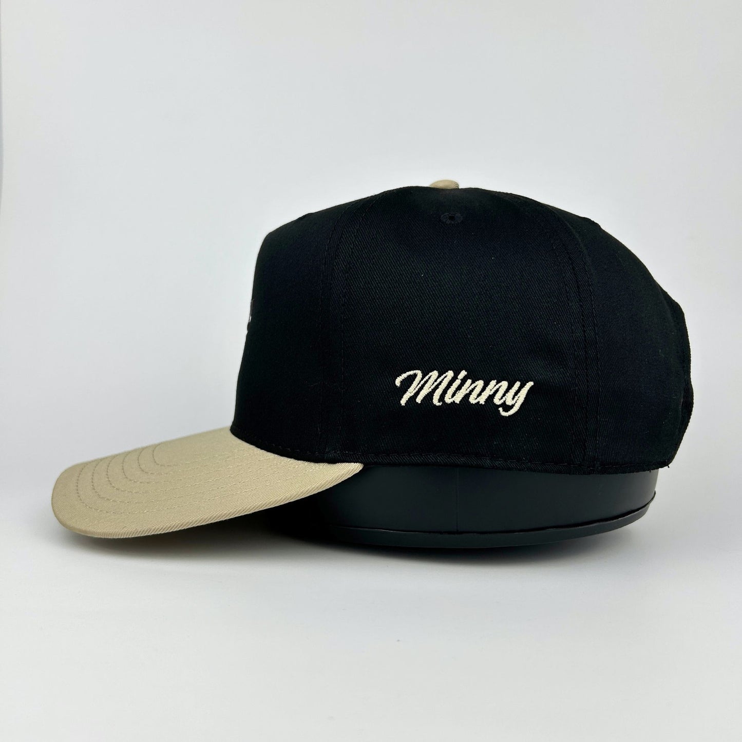 Black cap with beige visor and 'Minny' embroidery on a white background