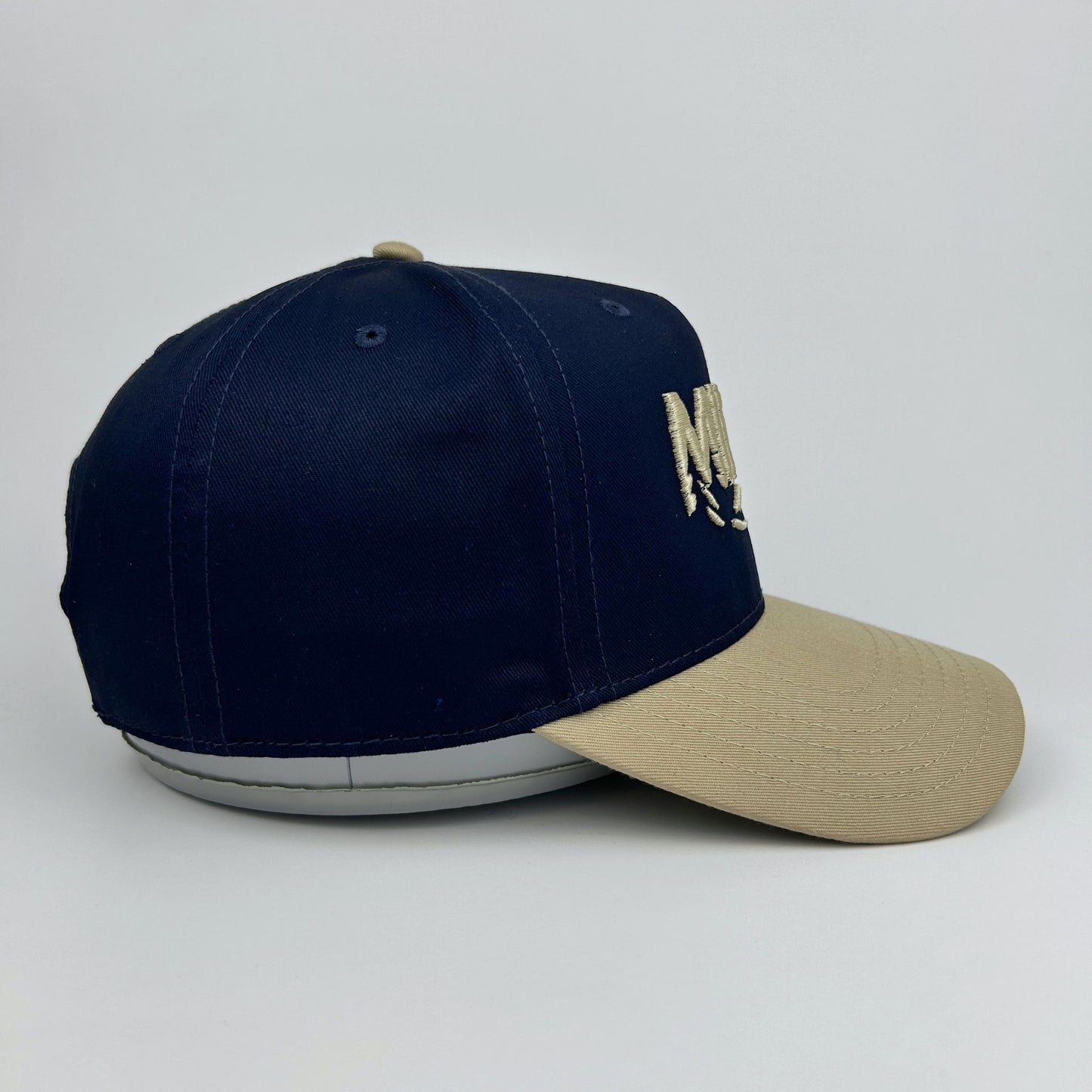 Two-tone navy and beige cap on a light gray background