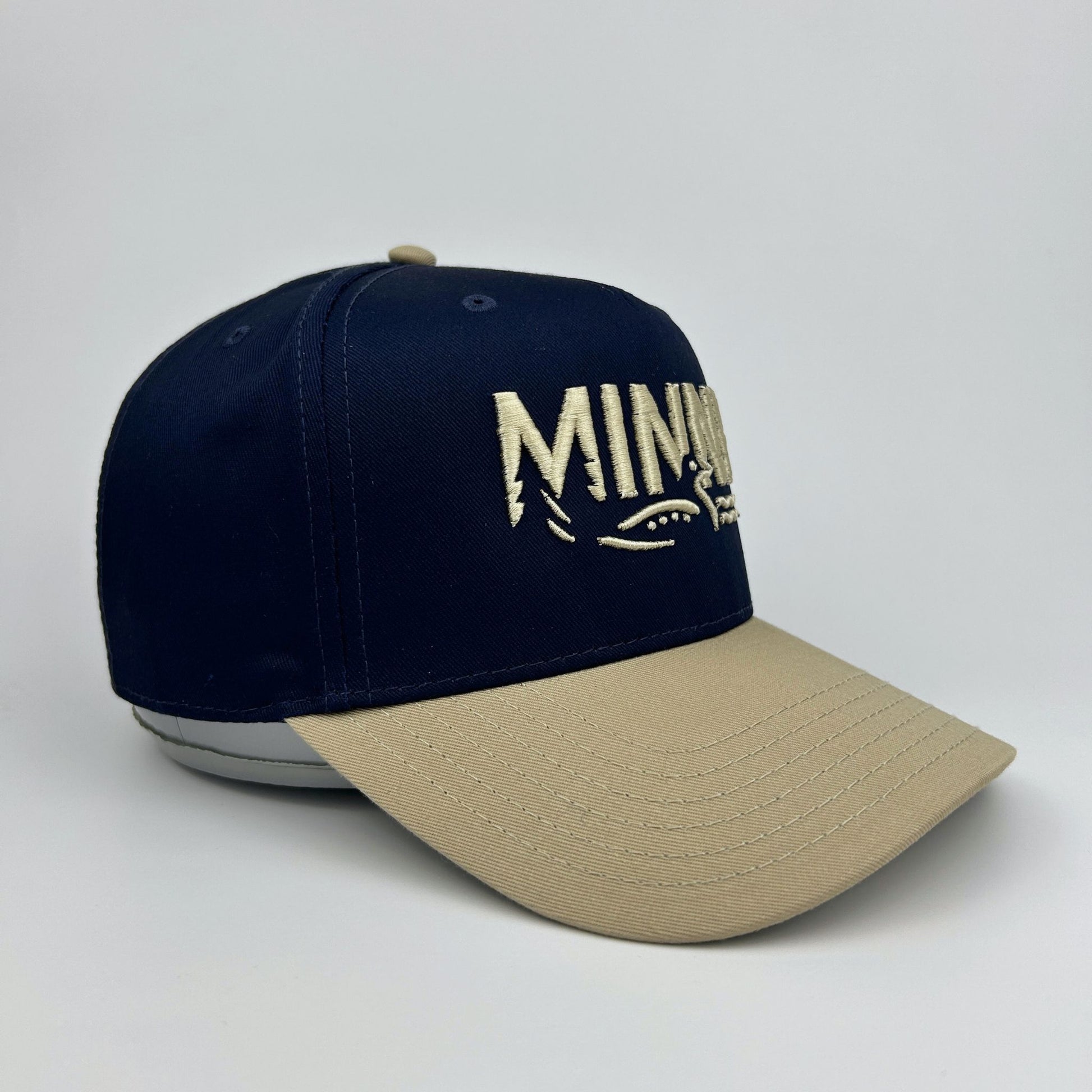 Navy and beige cap with 'Minny' logo on a light gray background