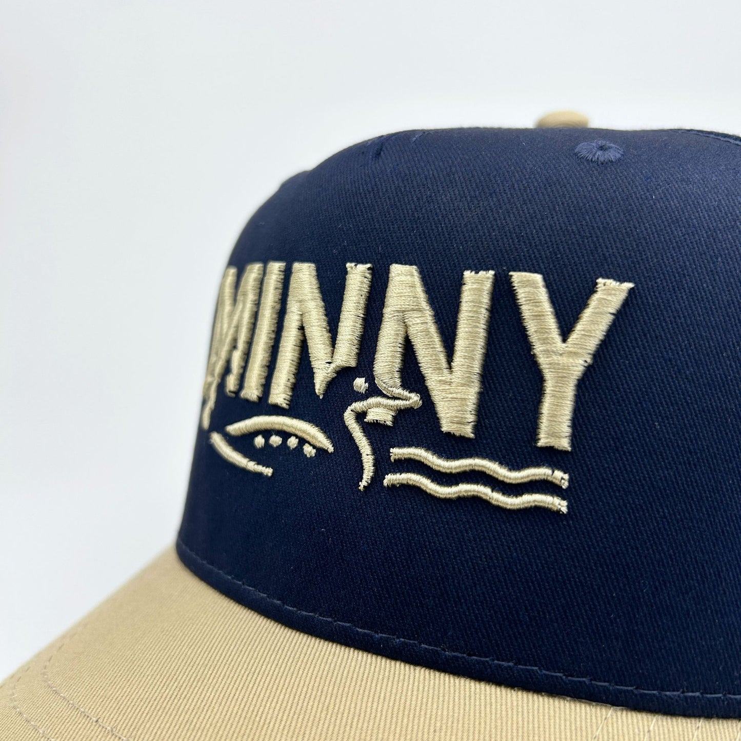 Navy and beige cap with 'MINNY' branding on a white background