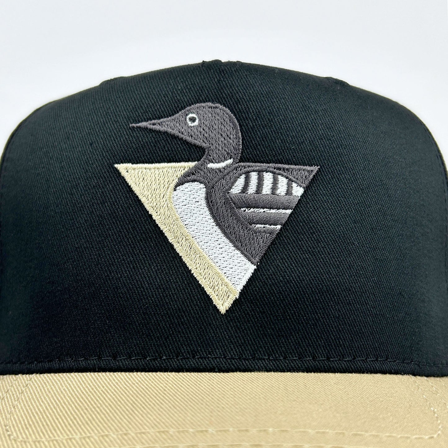 Black and beige cap with a loon logo on a white background