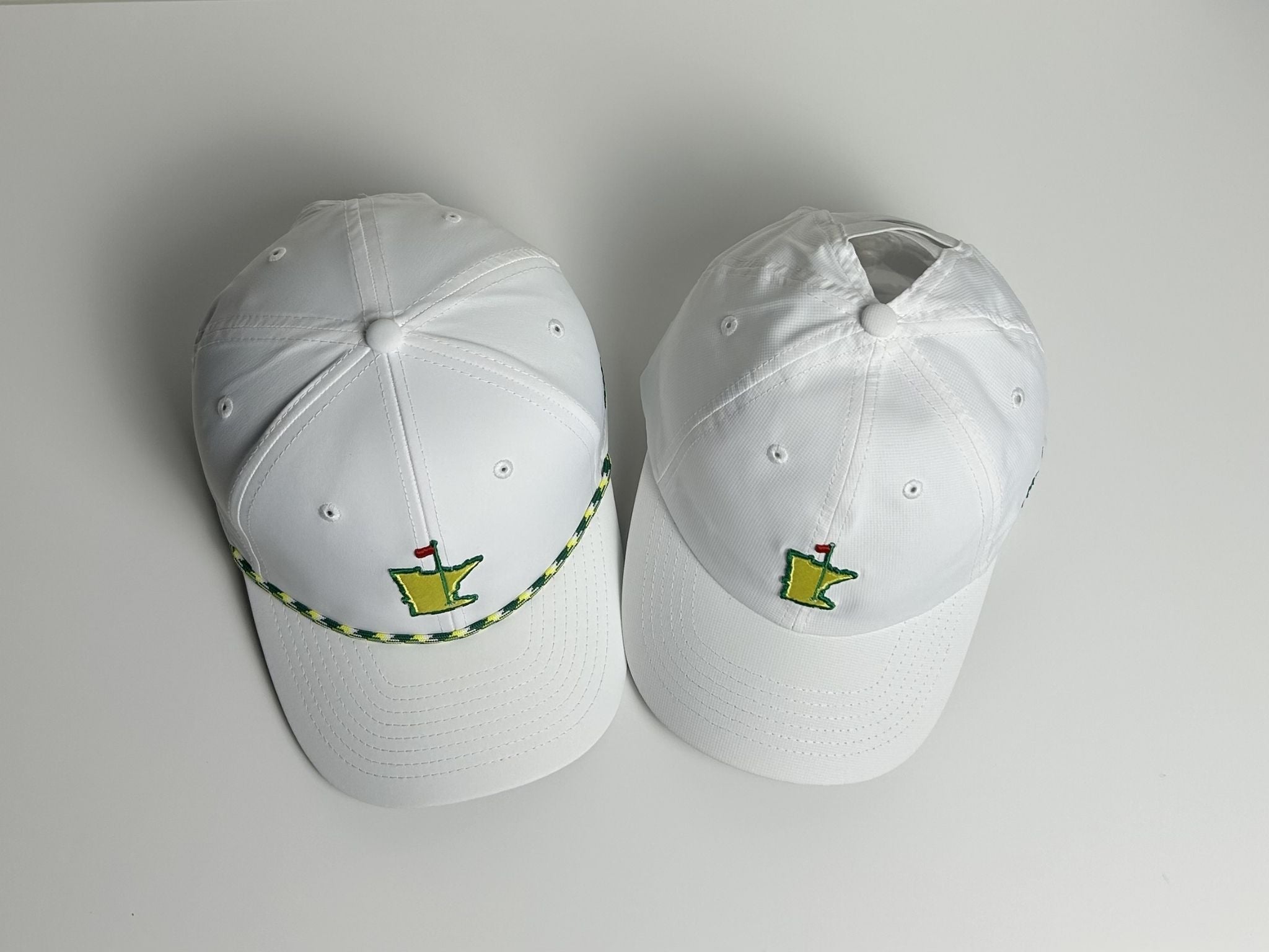 Two white baseball caps with embroidered logos on a light gray background