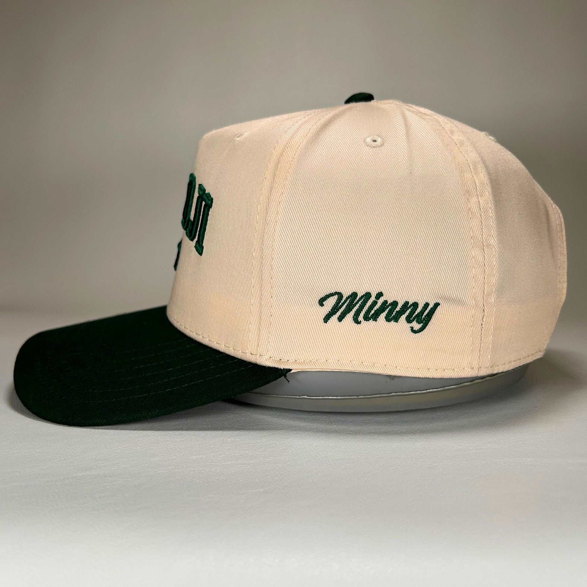 Side branded view of of natural and green Bemidji 5-panel cap with puff lettering