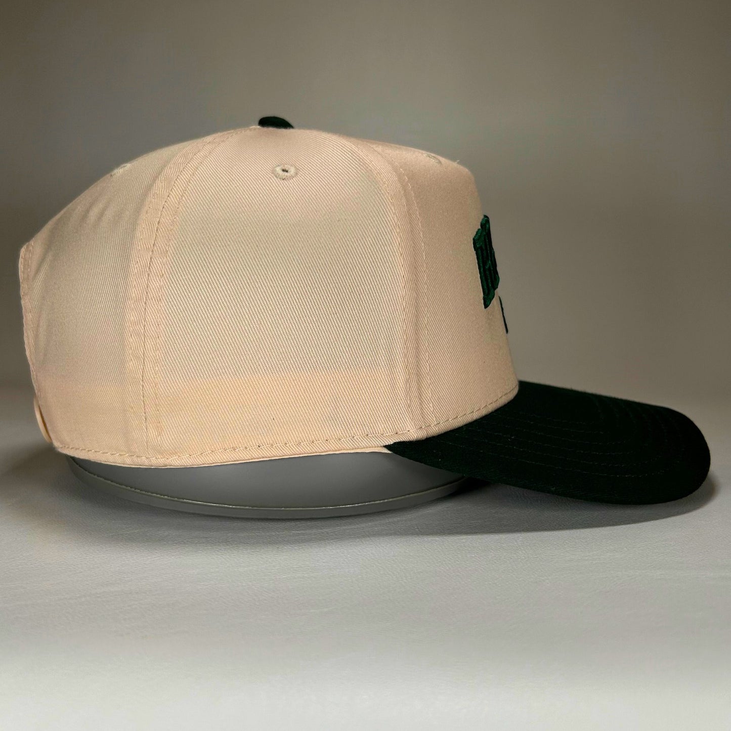 side view of natural and green Bemidji 5-panel cap with puff lettering